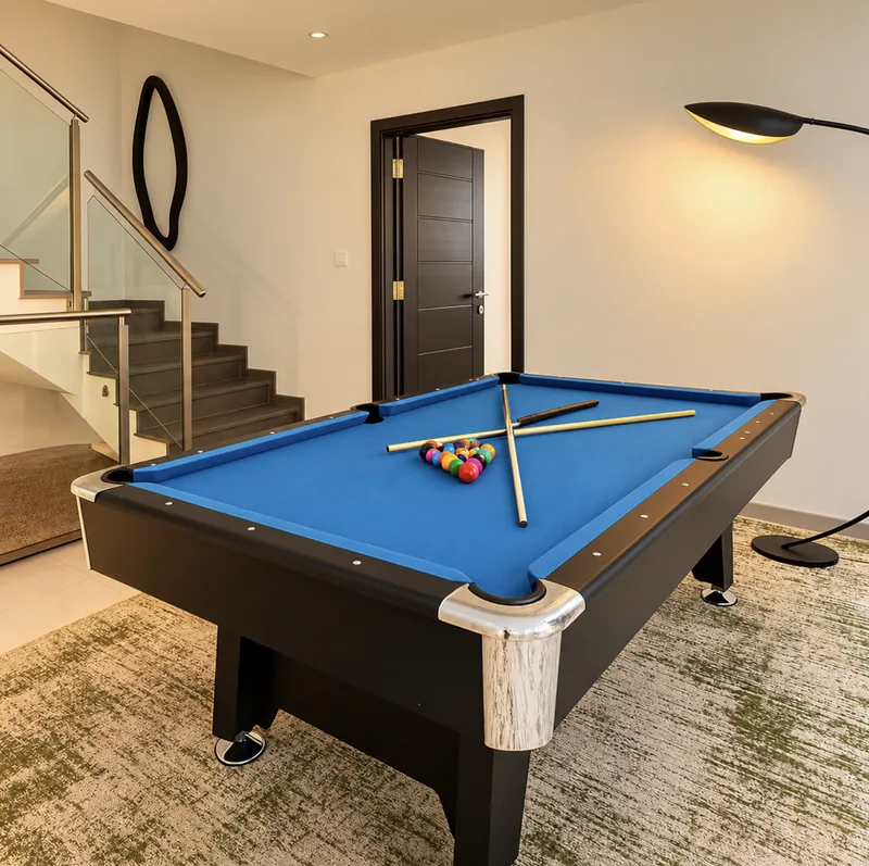 Dunia games room with blue-felt pool table, arc floor lamp and staircase