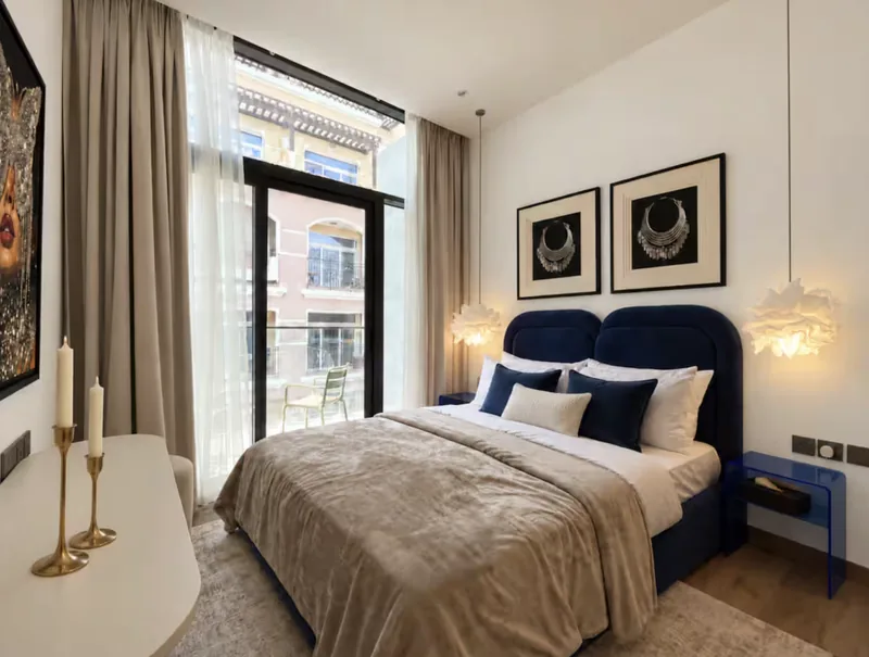 Mirage bedroom with navy headboard, framed prints, feather pendant lights and balcony doors