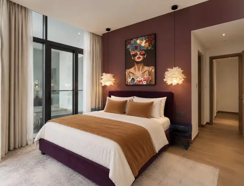Mirage bedroom with plum feature wall, pop-art portrait, king bed and balcony doors