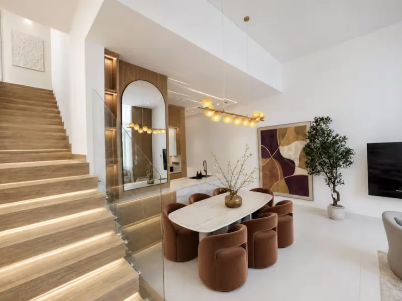 Mirage dining area and lit staircase with arched mirror niche, abstract artwork and olive tree
