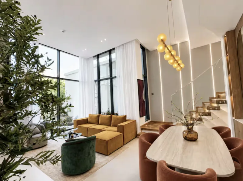 Mirage open-plan living and dining area with mustard sofa, green velvet armchair, oval dining table and floating staircase