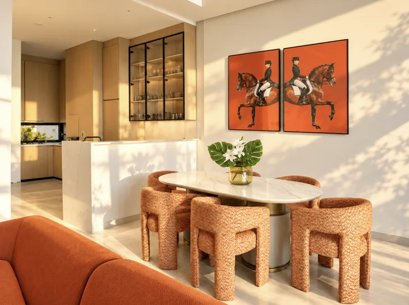 ParkView dining area with oval marble table and textured armchairs, opening onto the light-oak kitchen