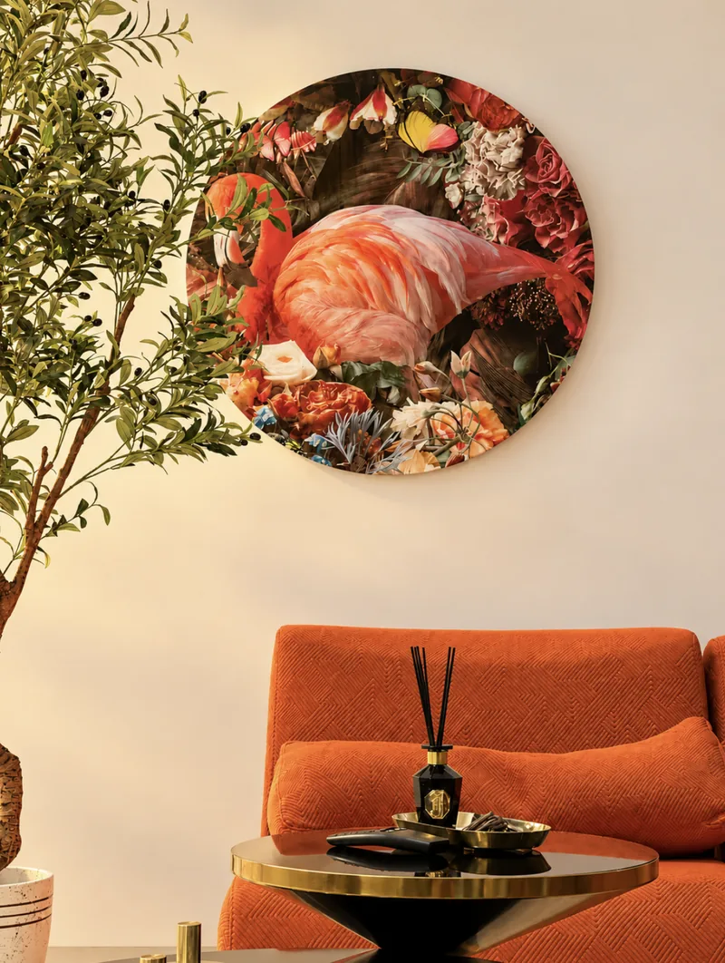 Round flamingo-and-flowers artwork above the orange sofa with an olive tree and gold side table