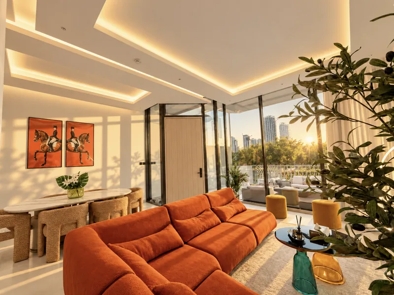 ParkView open-plan living room with orange sofa, dining table and floor-to-ceiling glass onto the terrace and greenery