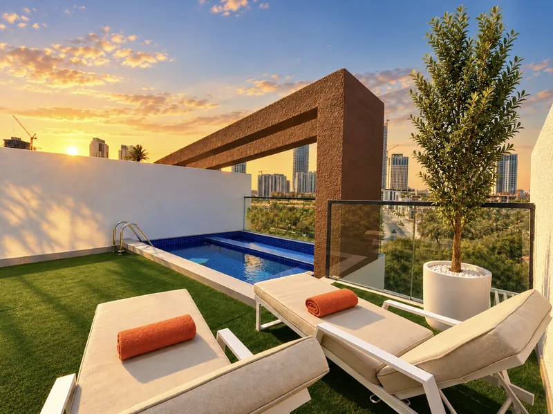 ParkView private rooftop plunge pool with blue mosaic tiles, two sun loungers on artificial grass and city towers beyond