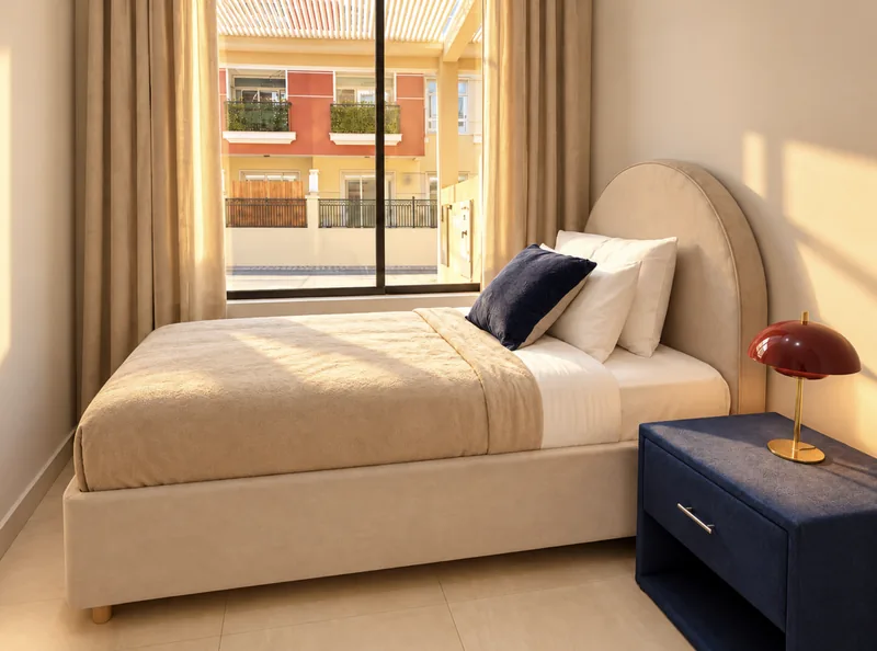ParkView single bedroom with arched upholstered headboard, navy nightstand and burgundy mushroom lamp
