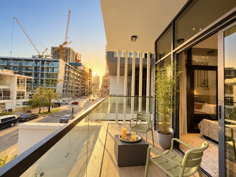 Pearl balcony with green chairs, juice tray and glass railing overlooking the street