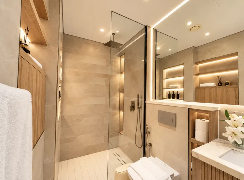 Pearl bathroom with walk-in rainfall shower, white slatted floor, wall-hung WC and wood niches