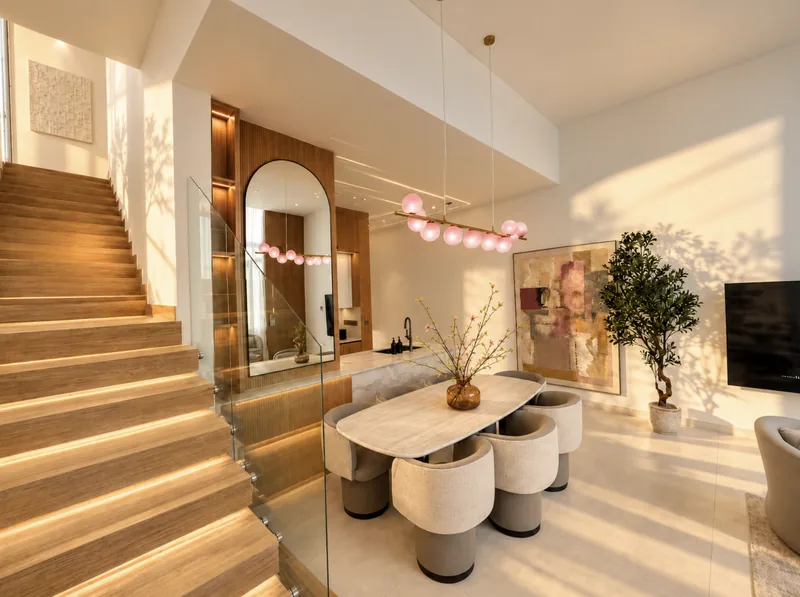 Pearl dining area with marble table and pink globe pendant, kitchen island and LED-lit staircase beyond