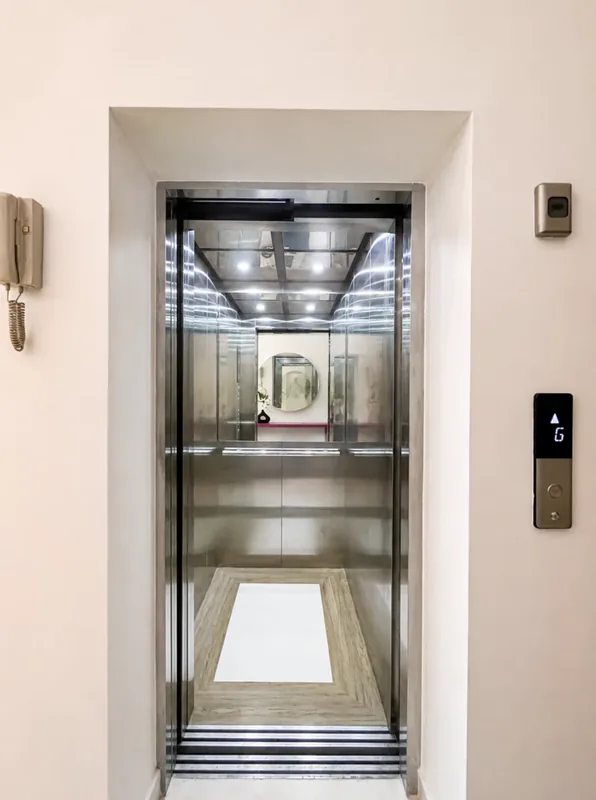 Pearl private lift with open brushed-steel doors and hallway call panel
