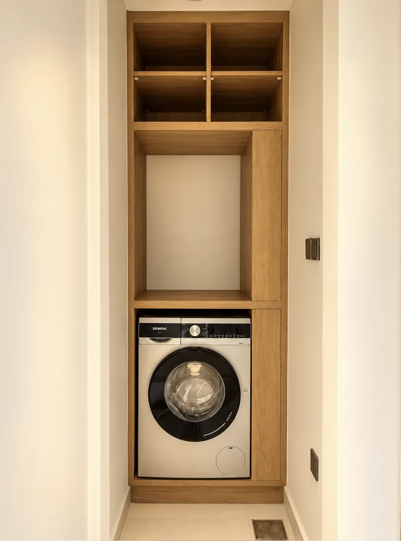 Pearl laundry with front-loading washing machine built into light-wood shelving