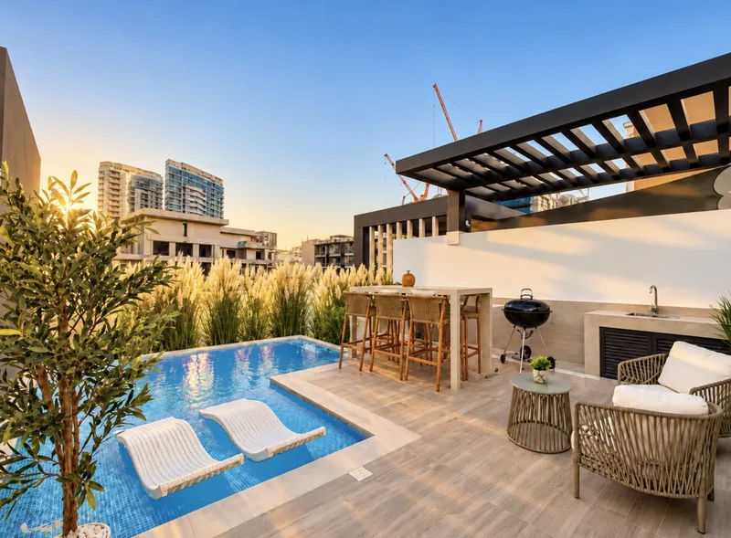 Pearl rooftop terrace at sunset with blue pool, two in-pool loungers, pergola, bar with stools, BBQ grill and rattan armchairs